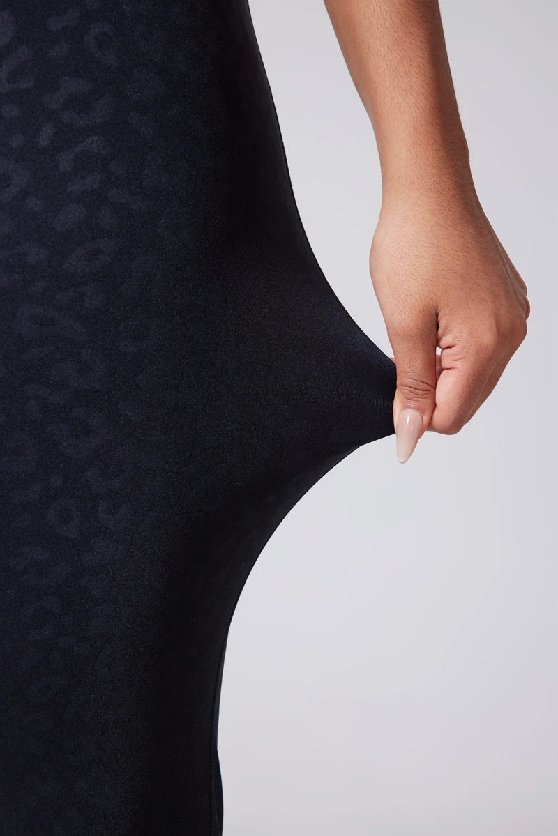 Close-up of a person wearing a black textured dress with a plain background