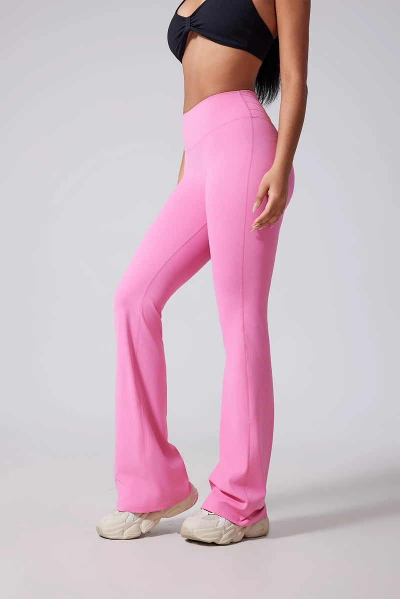 Person wearing petal  pink flared pants on a plain background.