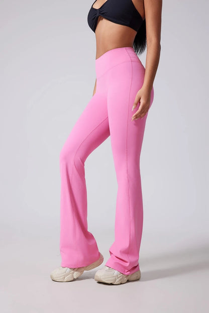 Person wearing petal  pink flared pants on a plain background.
