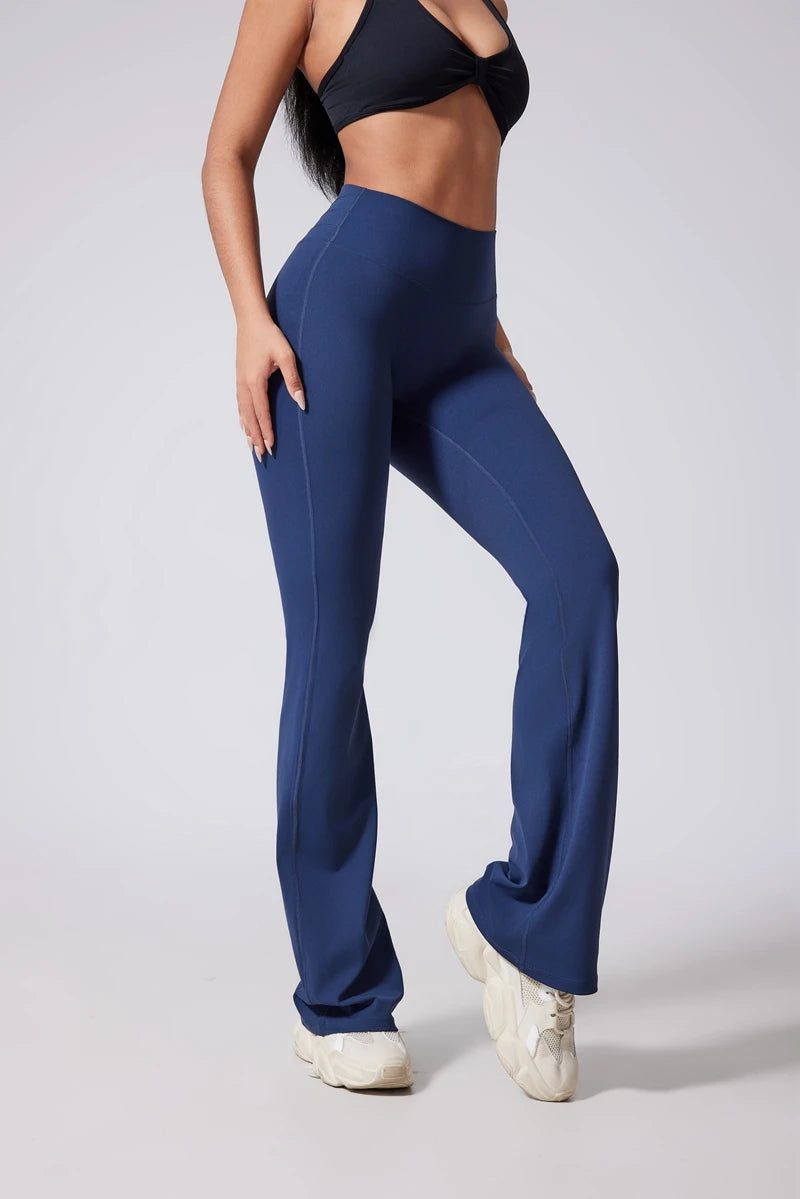 Person wearing blue flared pants and a black sports bra on a light gray background