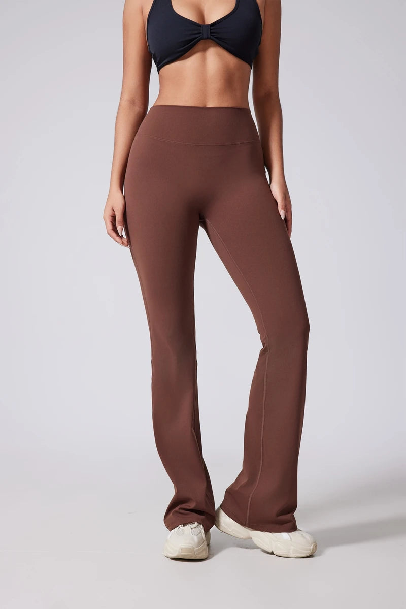 Person wearing brown high-waisted leggings and a black top on a light gray background