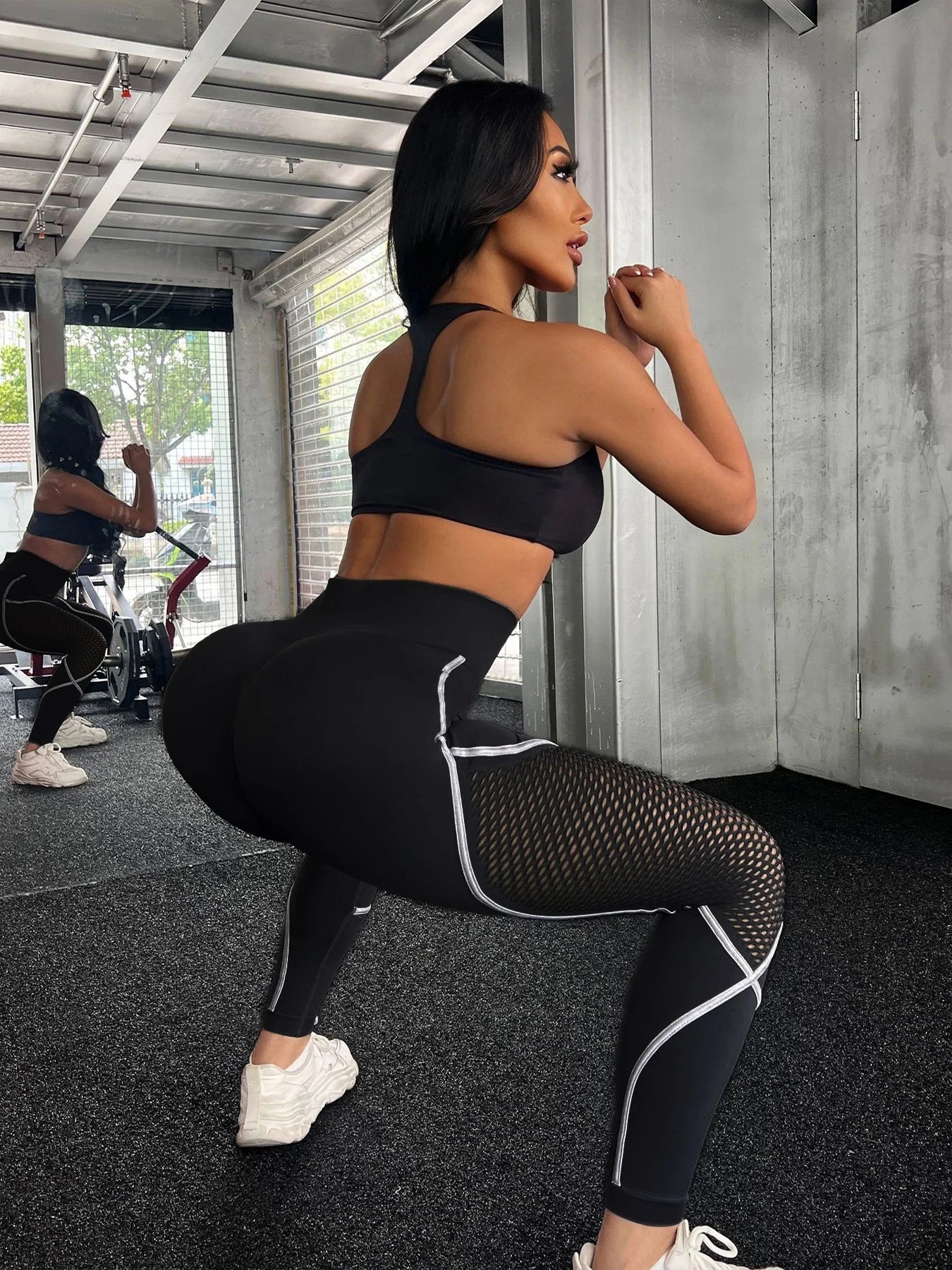 Woman in black athletic wear posing in a gym setting- Stealth Mode Black