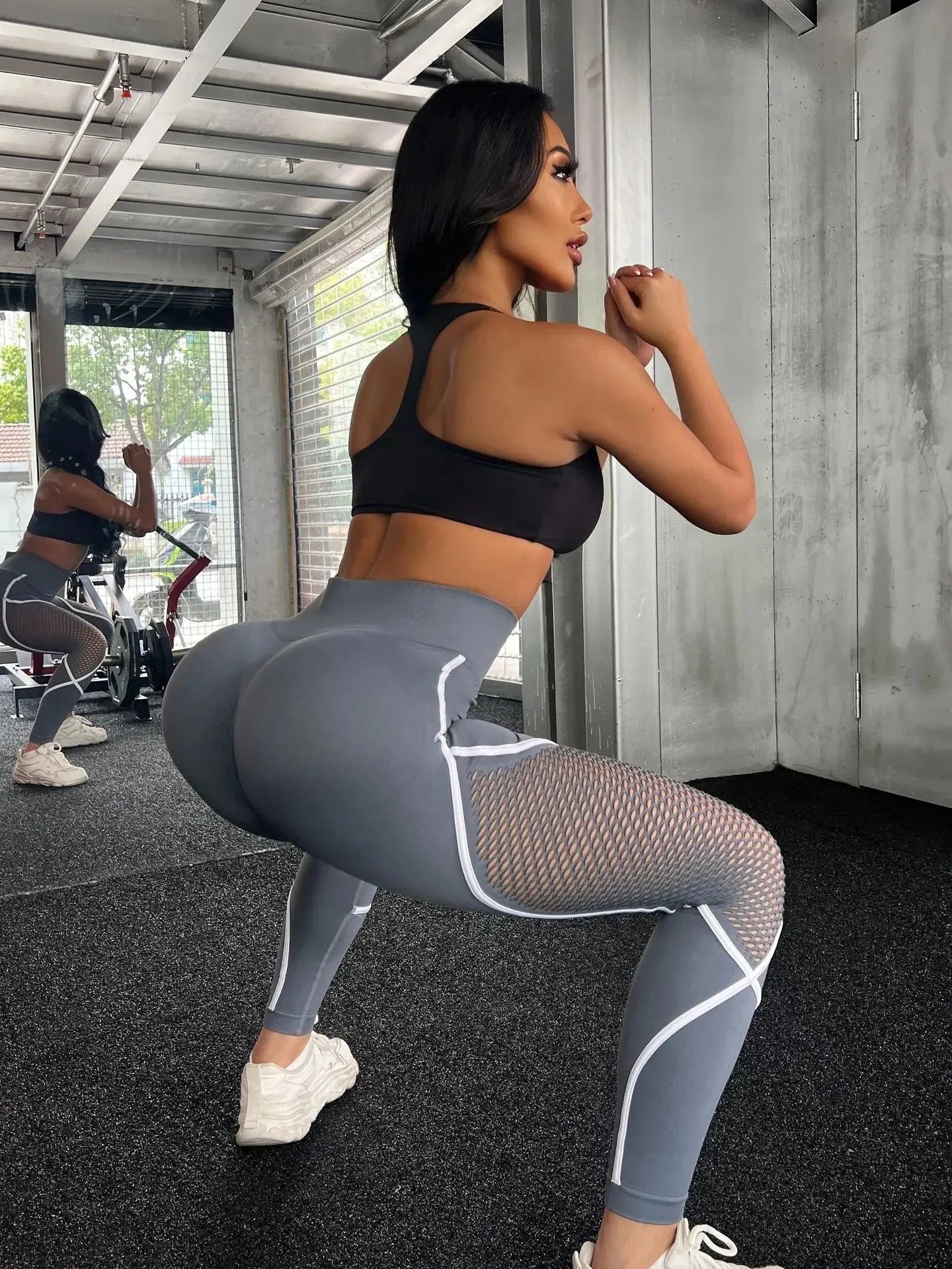 Model squatting in gray-blue leggings with mesh inserts and curved seams – Stormshade tone