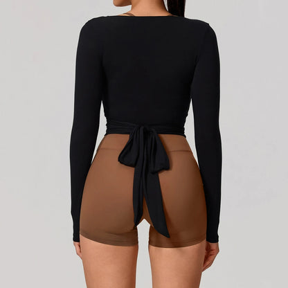 Person wearing a black long-sleeve top and brown shorts on a plain background