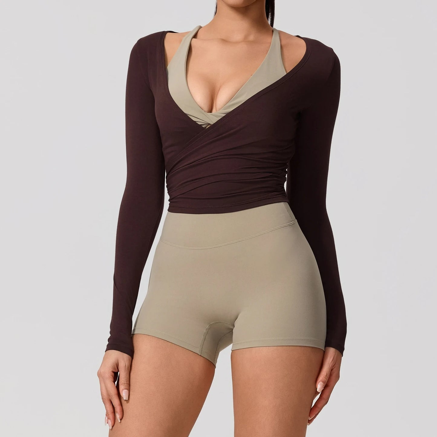 Person wearing a brown long-sleeve top and beige shorts on a gray background