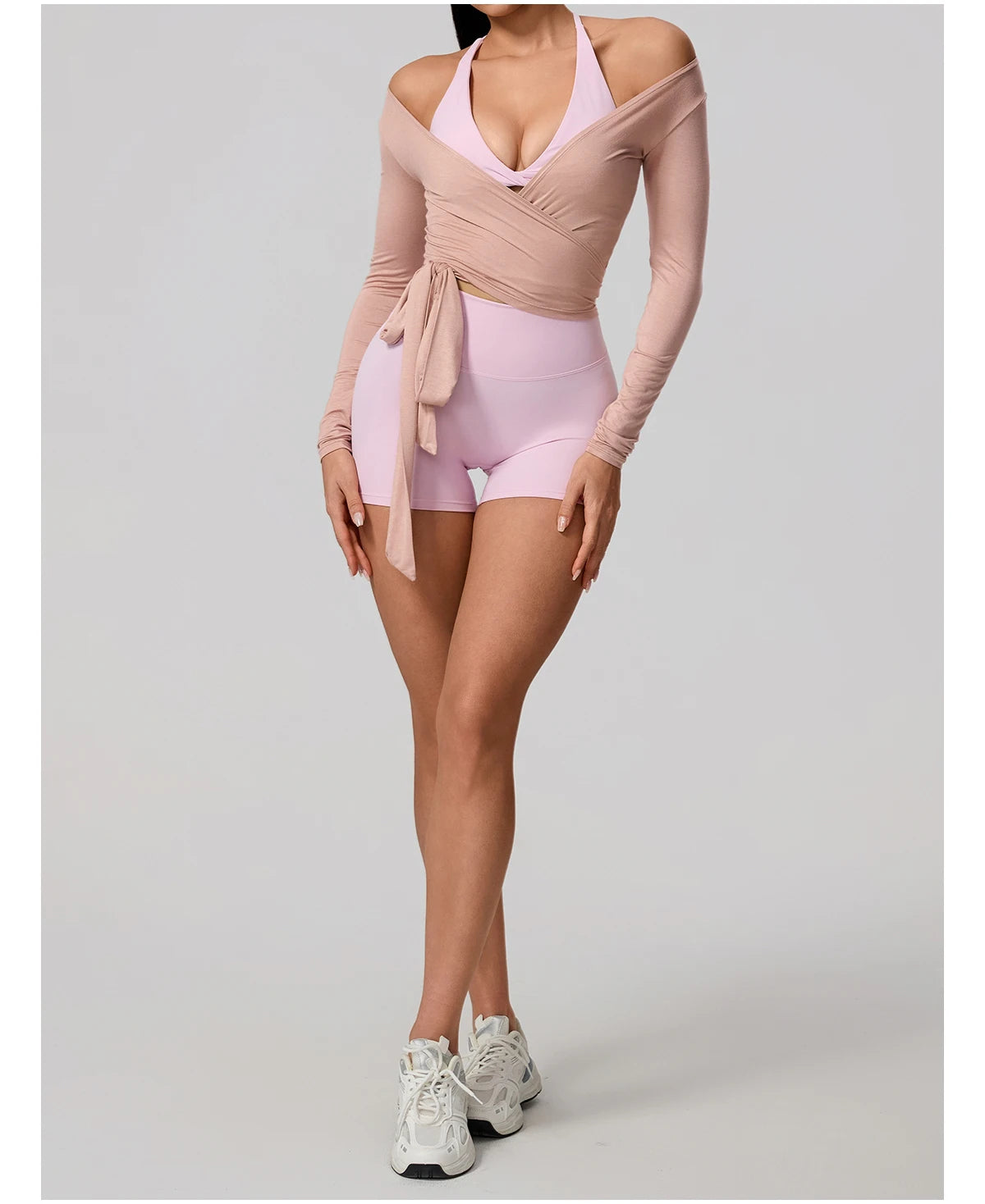 Person wearing a pink and beige outfit with white sneakers on a light gray background