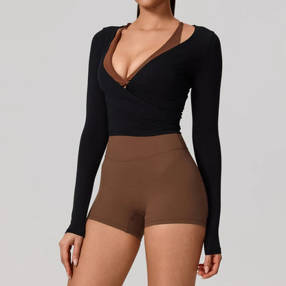 Person wearing a black long-sleeve top and brown shorts on a gray background