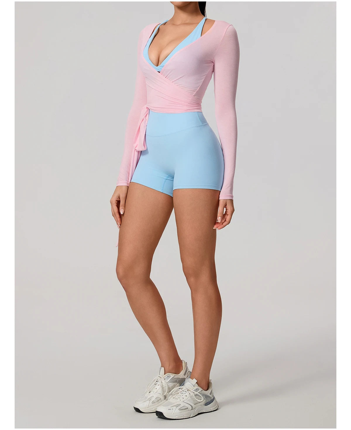 Person wearing a pink long-sleeve top and light blue bike shorts on a gray background
