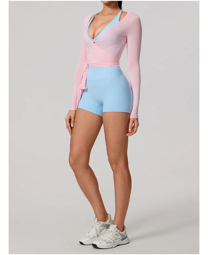 Person wearing a pink long-sleeve top and light blue bike shorts on a gray background