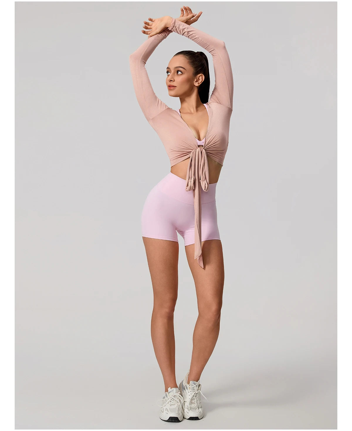 Woman in pink athletic outfit posing against a gray background