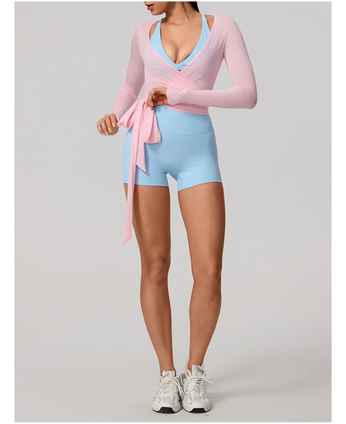 Person wearing a pink long-sleeve top and light blue shorts on a gray background