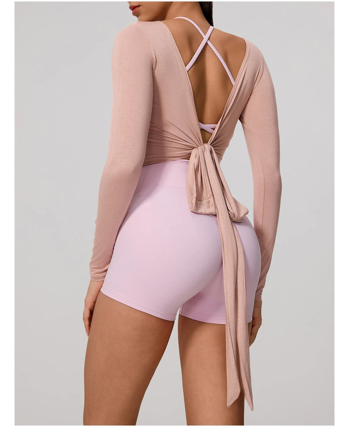 Person wearing a pink long-sleeve top and light pink shorts on a plain background