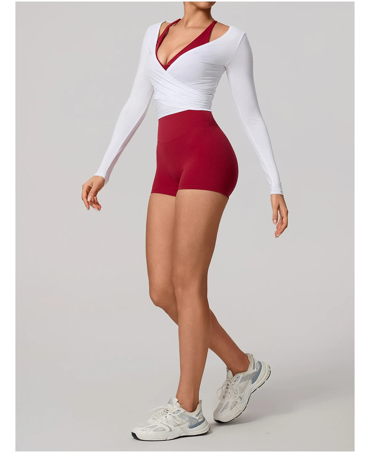 Person wearing a white long-sleeve top and red high-waisted shorts on a gray background