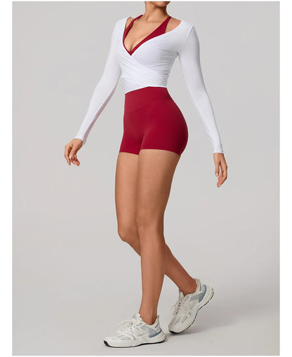 Person wearing a white long-sleeve top and red high-waisted shorts on a gray background